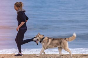 ragazza che corre sulla spiaggia con husky
